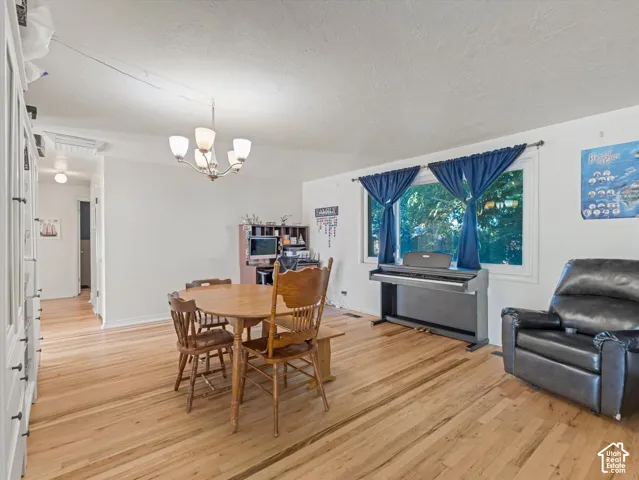 Wood-finish flooring, neutral walls, large picture window, and multi-arm chandelier