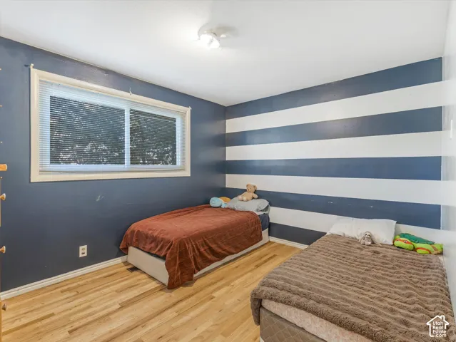 Interior space featuring wood-finish flooring, a sliding window with horizontal blinds, and a ceiling-mounted light fixture