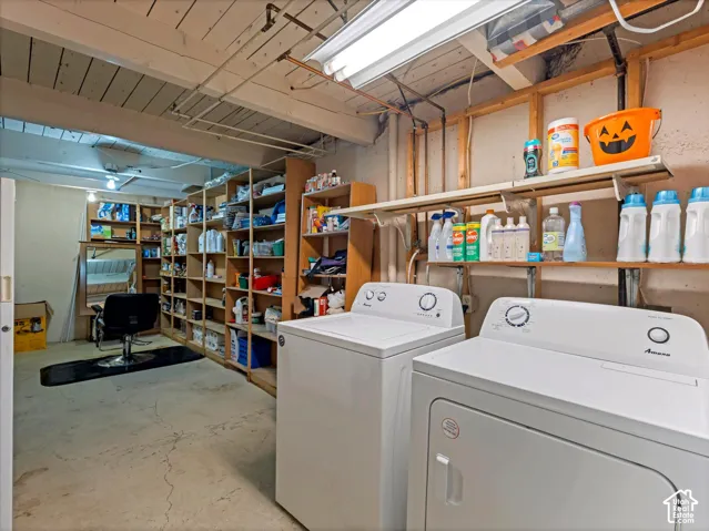 Utility area featuring exposed ceiling joists, concrete flooring, and extensive wall-mounted shelving