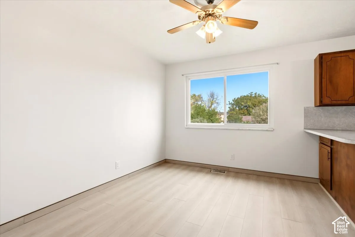 Wood-finish flooring, sliding window, ceiling fan with integrated lighting, and built-in wood cabinetry