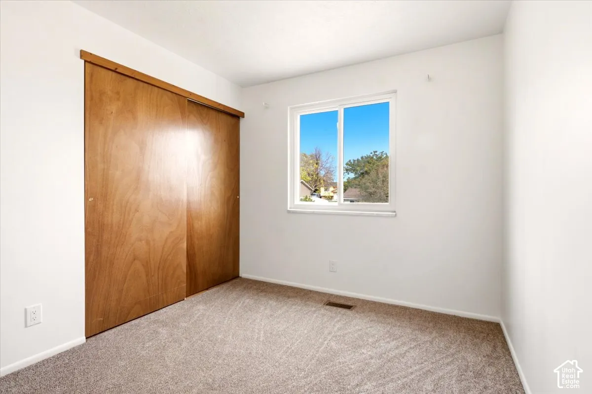 Room featuring neutral wall-to-wall carpeting, sliding wood-finish closet doors, and a horizontal sliding window