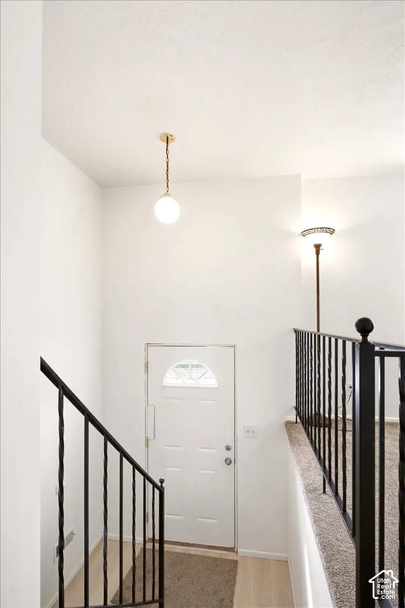 Entryway featuring a white exterior door with a semi-circular transom window, black iron railing, and a globe pendant light fixture