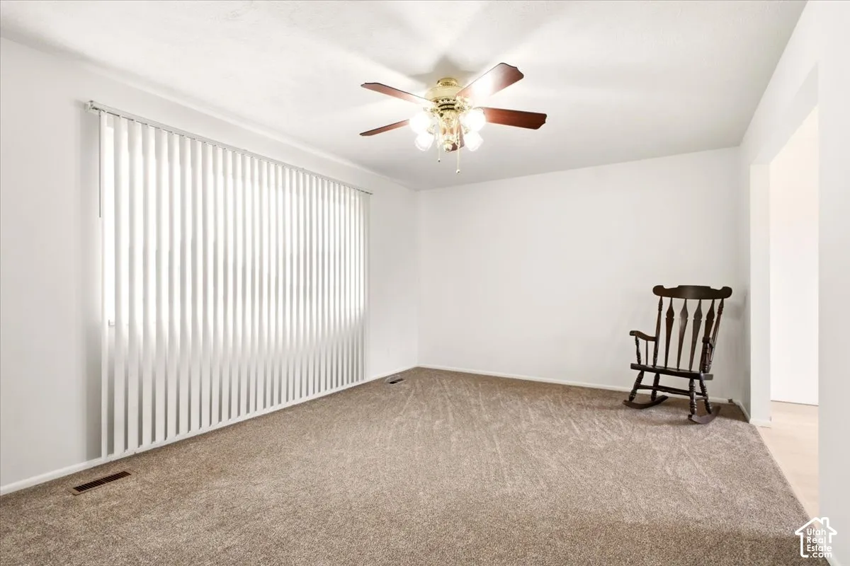 Neutral wall palette, carpeting, ceiling-mounted light fixture with fan, and vertical window blinds