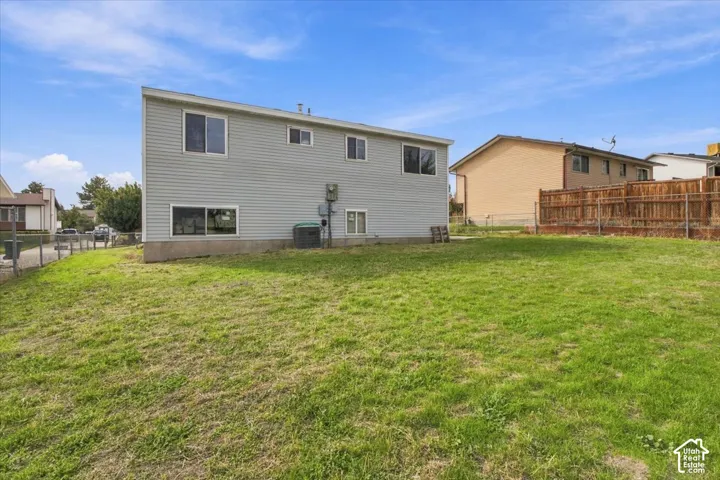 Vinyl-sided exterior featuring horizontal siding, concrete foundation, metal-framed sliding windows, and a fenced yard with grass lawn