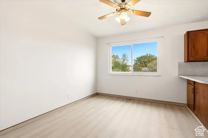 Wood-finish flooring, sliding window, ceiling fan with integrated lighting, and built-in wood cabinetry