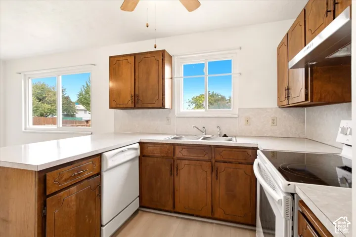 Kitchen featuring stained wood cabinetry, white countertops, double-basin stainless steel sink, and wood-finish flooring