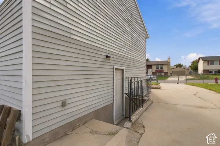 Horizontal siding exterior with a concrete driveway and an exterior access door featuring a metal railing