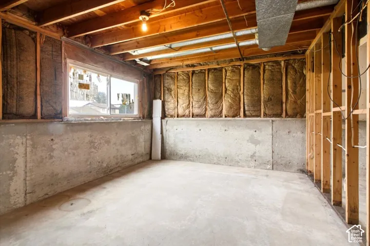 Unfinished space featuring exposed wood framing, concrete foundation walls, insulation, and a sliding window