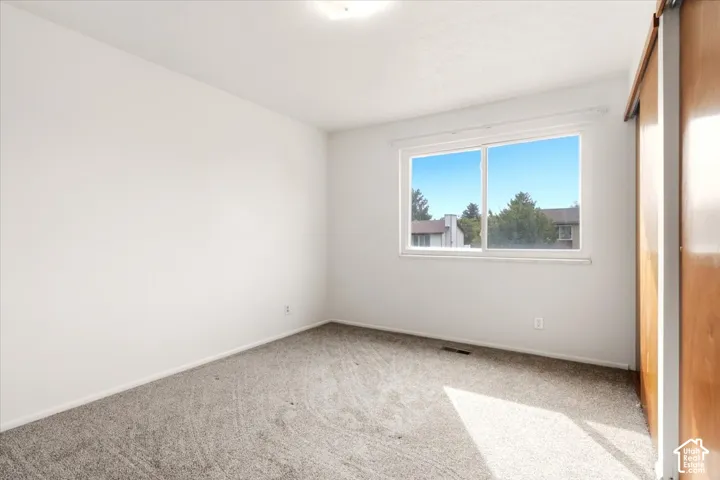 Neutral-toned wall-to-wall carpeting, sliding-panel wood-finish closet doors, and a double-pane sliding window