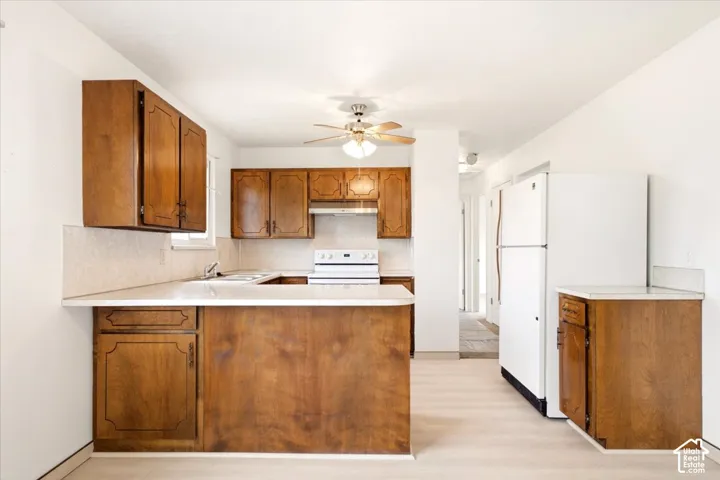 Kitchen featuring wood cabinetry, light-toned countertops, tile backsplash, built-in range hood, and light-toned flooring
