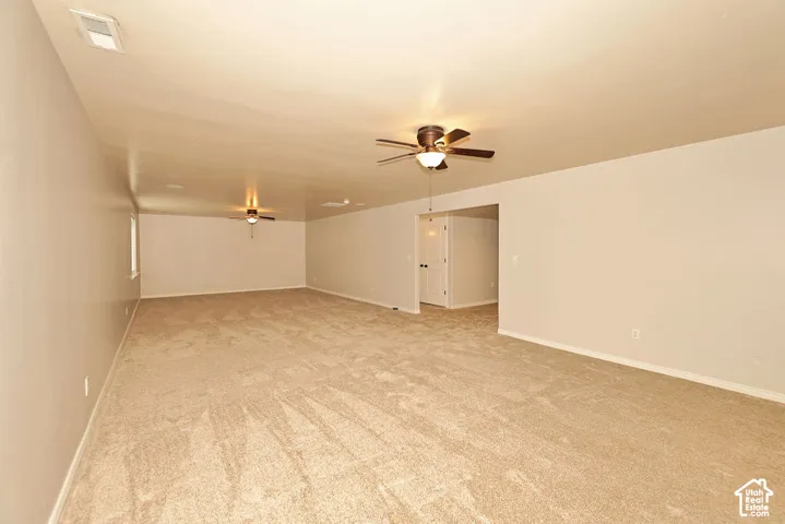 Spacious room featuring wall-to-wall carpeting, neutral paint, and dual ceiling fans
