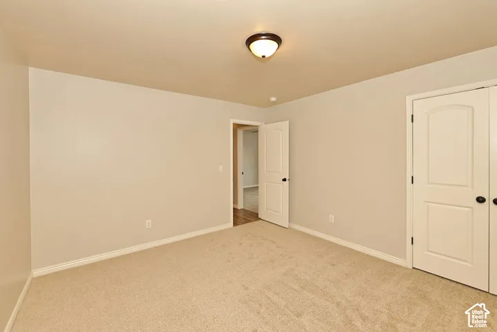 Interior room featuring neutral wall paint, wall-to-wall carpeting, a dome-style ceiling light fixture, and two-panel interior doors