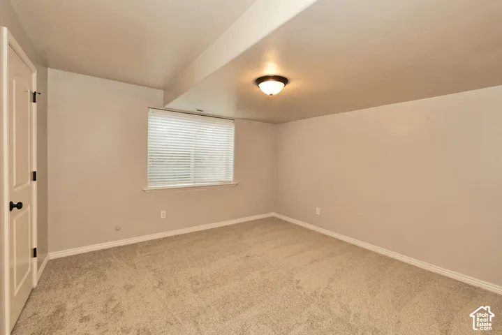 Room featuring neutral carpeting, a window with horizontal blinds, and a flush-mount ceiling light fixture