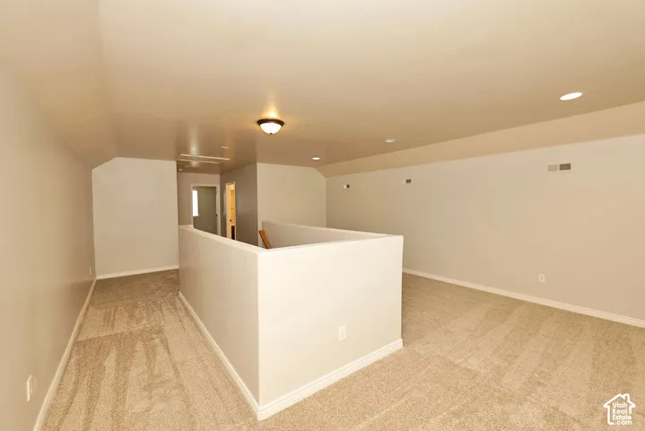 Open-concept bonus space featuring neutral carpeting, recessed lighting, and sloped ceiling architecture