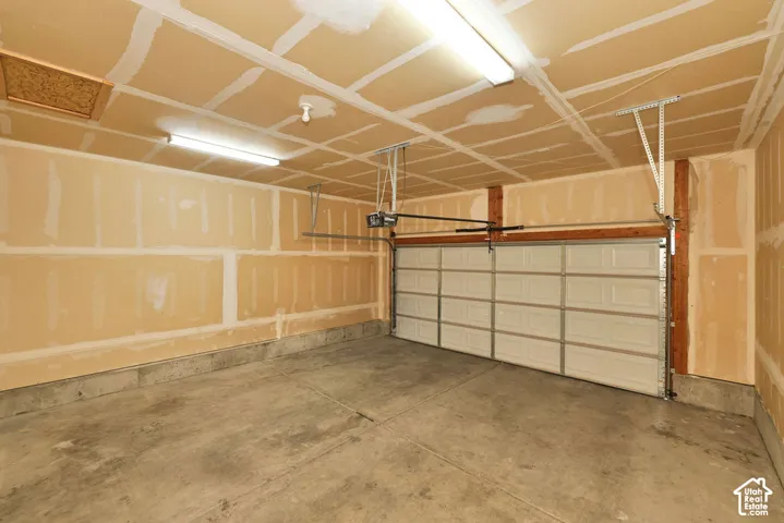 Attached garage featuring a concrete floor, sectional garage door, and dual overhead light fixtures