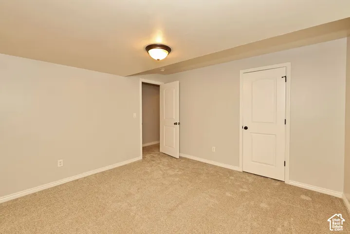 Interior room featuring neutral-toned carpeting, two-panel arched interior doors with dark hardware, and a flush-mount ceiling light fixture