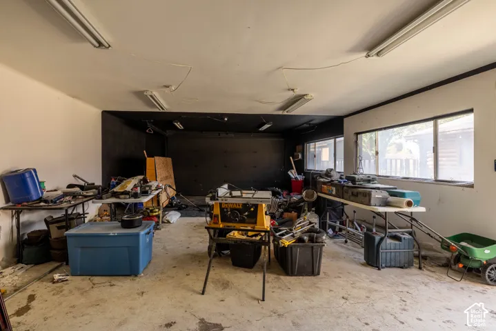 Garage interior featuring concrete flooring, fluorescent overhead lighting, and horizontal windows providing natural light