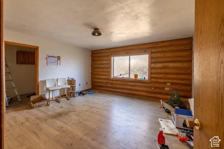 Interior space featuring horizontal log walls, wood-finish flooring, and a window with wood trim