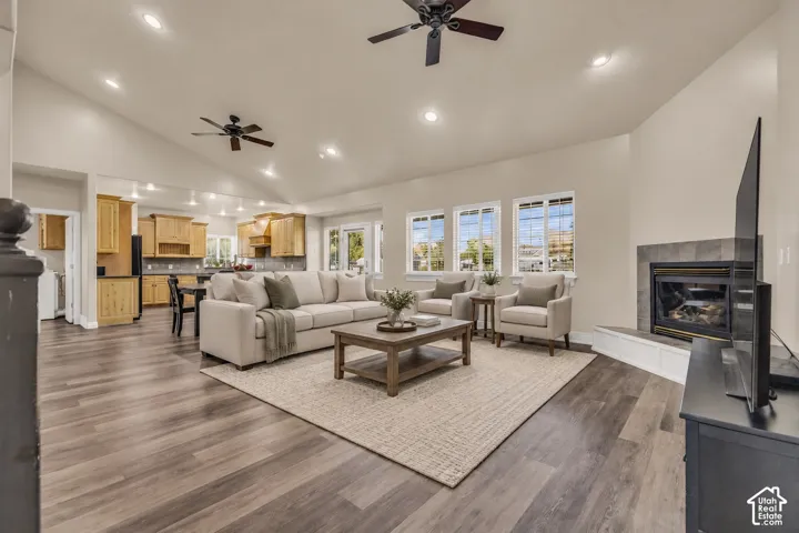Vaulted ceiling with dual ceiling fans, wood-finish flooring, recessed lighting, and corner fireplace with tile surround