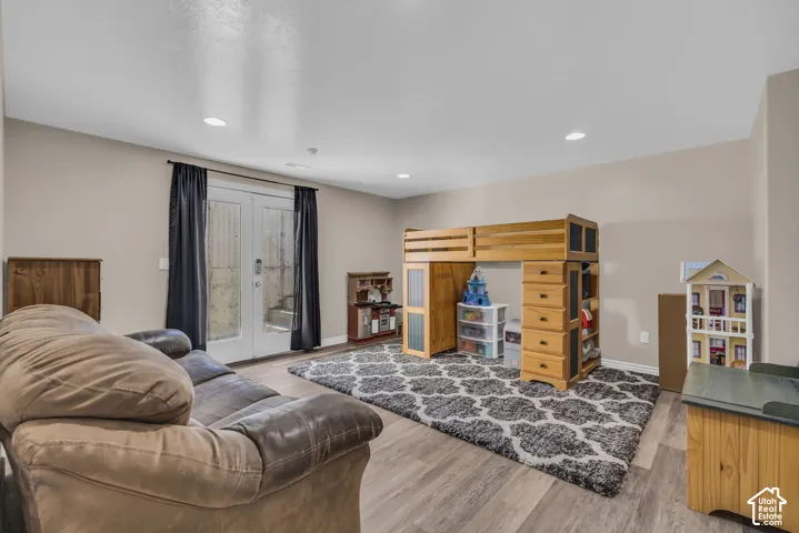Wood-finish flooring, recessed lighting, and full-glass panel French doors with direct outdoor access