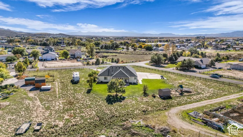 Expansive lot featuring a concrete driveway, mature trees, fenced perimeter, and mountainous horizon