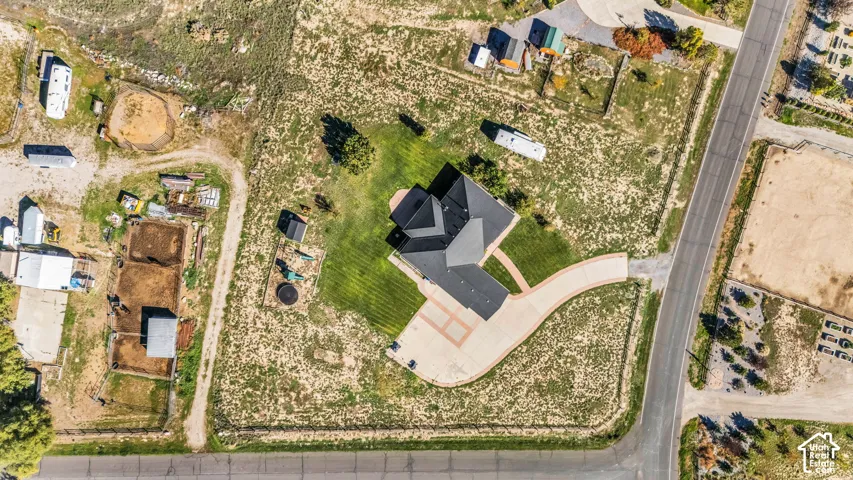 Aerial perspective of property featuring a multi-pitched roofline, expansive lot, concrete driveway, and manicured lawn