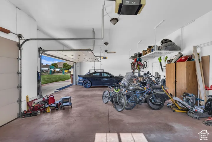 Multi-bay garage featuring overhead storage shelving, reinforced door hardware, and wall-mounted lighting