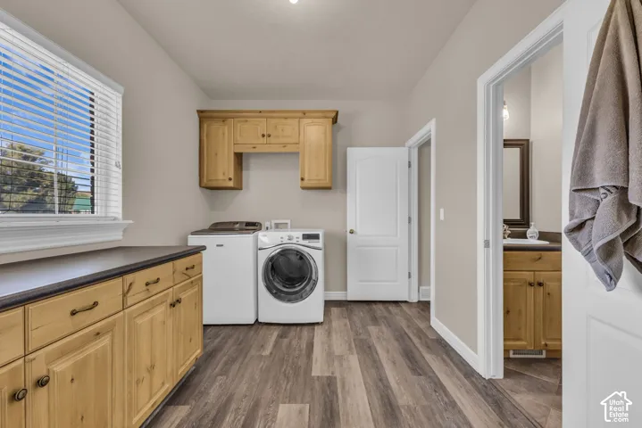 Laundry room featuring wood-finish cabinetry, solid-surface countertops, wood-finish flooring, and natural light via window blinds