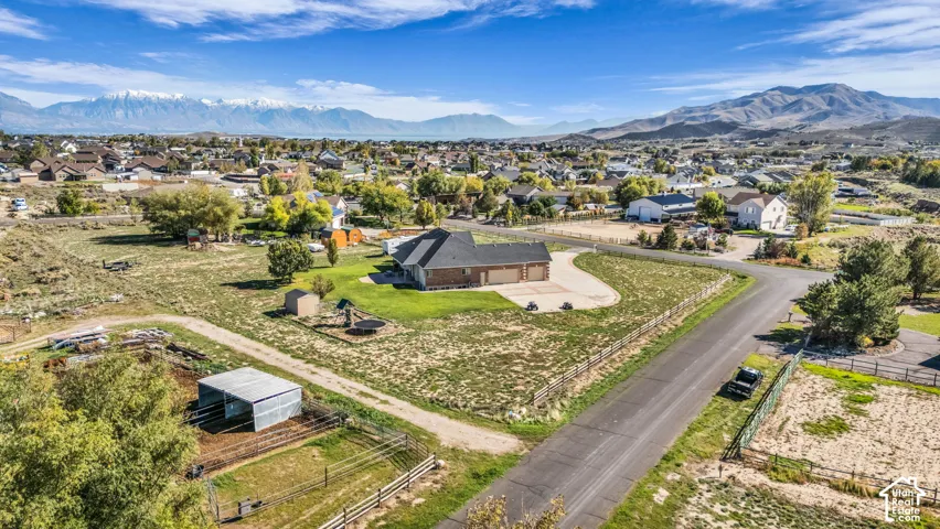 Single-story residence featuring a multi-car garage, expansive lot, exterior fencing, and a mountain backdrop