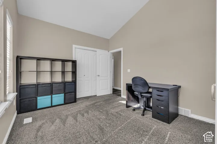 Room featuring vaulted ceilings, neutral wall tones, wall-to-wall carpeting, and a dual-panel closet door