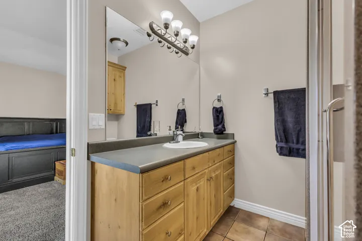 Bathroom vanity featuring natural wood-finish cabinetry, a solid-surface countertop, an integrated round sink, a full-width wall mirror, and five-bulb vanity lighting