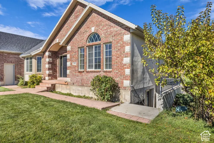 Traditional brick exterior featuring stone-accented corners, arched window detailing, and an integrated basement stairwell with concrete landing
