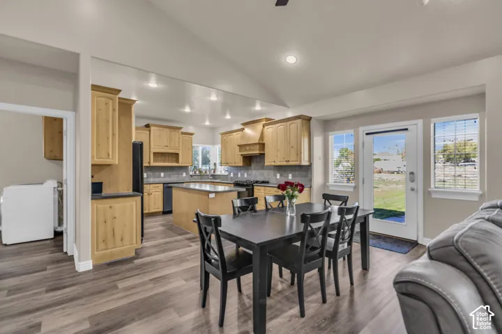 Vaulted ceiling kitchen featuring wood-finish cabinetry, center island, recessed lighting, and wood-finish flooring