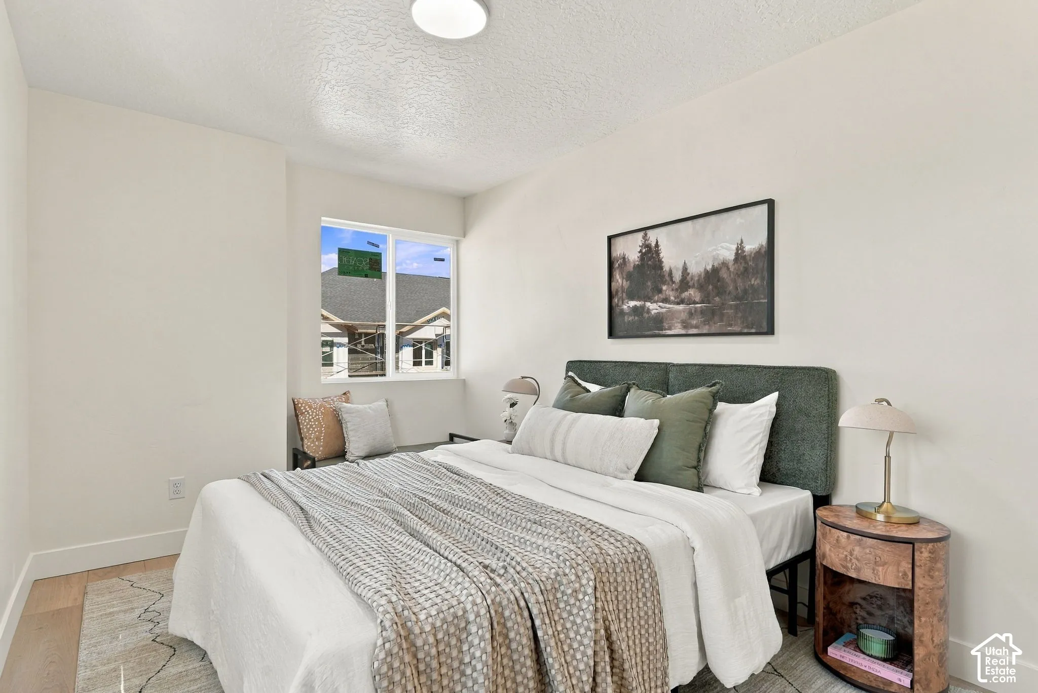Neutral-toned bedroom featuring light wood-finish flooring, crisp white walls, and a recessed window
