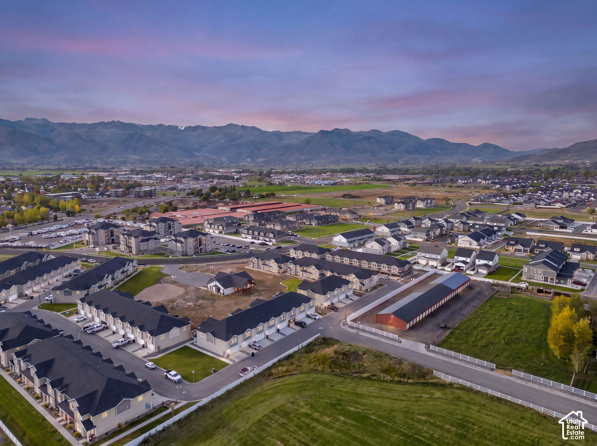 Aerial perspective of multi-family residential structures featuring asphalt shingle roofing, paved roadways, and mountain range backdrop