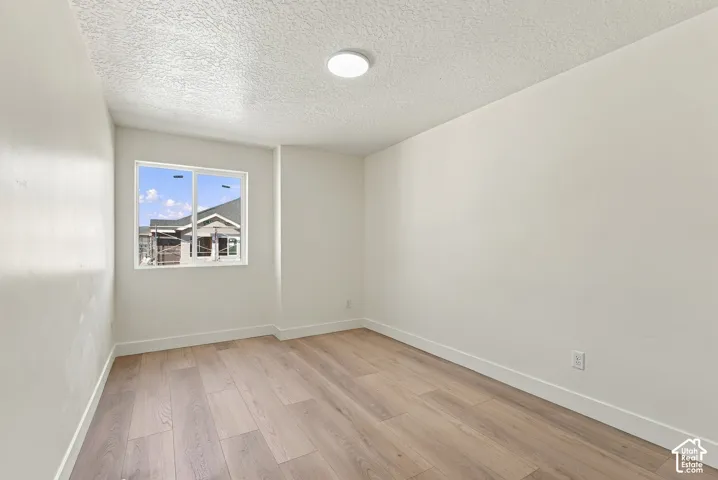Interior room featuring wood-finish flooring, white walls, a single-pane sliding window, and a flush-mount circular ceiling light