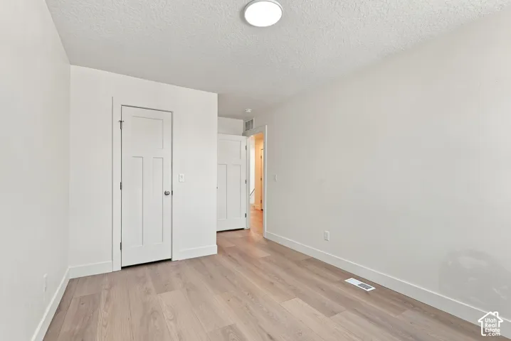 Interior room featuring wood-finish flooring, white walls, and two-panel shaker-style interior doors with brushed nickel hardware