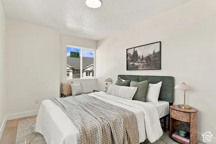 Neutral-toned bedroom featuring light wood-finish flooring, crisp white walls, and a recessed window