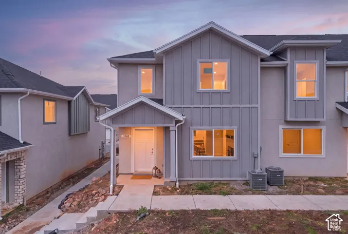 Modern two-story exterior featuring vertical board-and-batten siding, a covered entryway with a recessed porch, gabled rooflines, and multi-pane windows