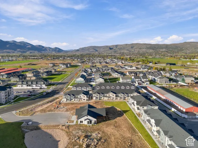 Aerial perspective featuring multi-family residential structures, paved streets, and a mountainous backdrop