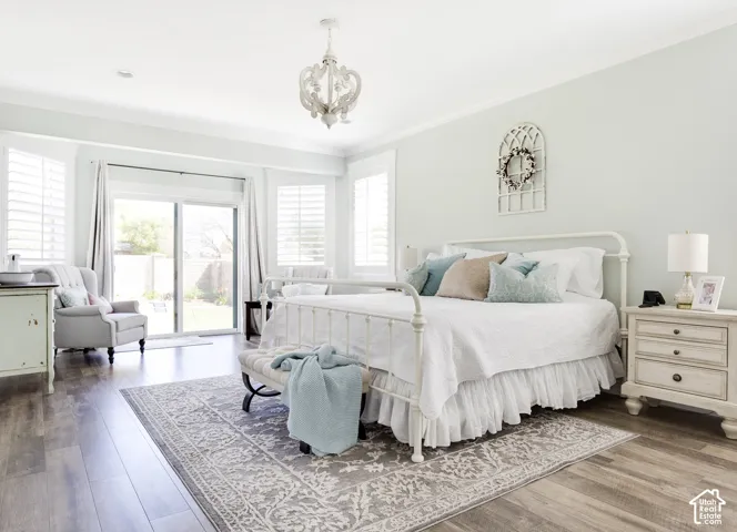 Wood-finish flooring, sliding glass door, white shutter window treatments, and decorative chandelier