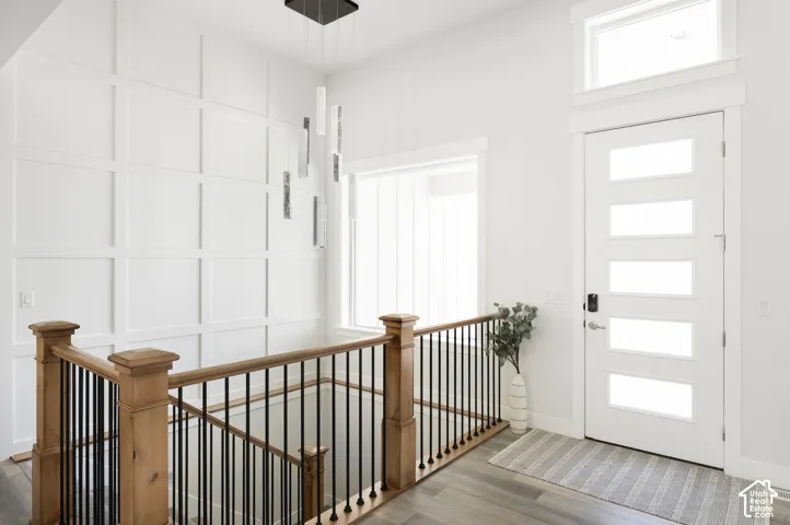 Entryway featuring square wall molding, wood-finish flooring, a five-panel glass insert door with a transom window, and a staircase with wood posts and metal balusters