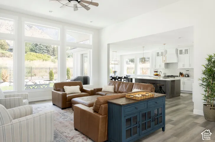 Open-concept interior featuring oversized windows, wood-finish flooring, a kitchen island with stone-surface countertop, and pendant lighting