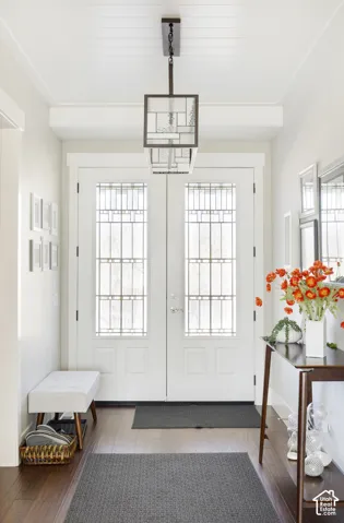 Entryway featuring double doors with decorative glass panels, wood-finish flooring, a tongue-and-groove paneled ceiling, and a geometric-style pendant light fixture
