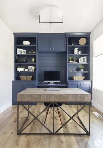 Custom floor-to-ceiling built-in cabinetry with horizontal shiplap detailing, integrated desk surface, wood-finish flooring, and modern geometric drum ceiling light