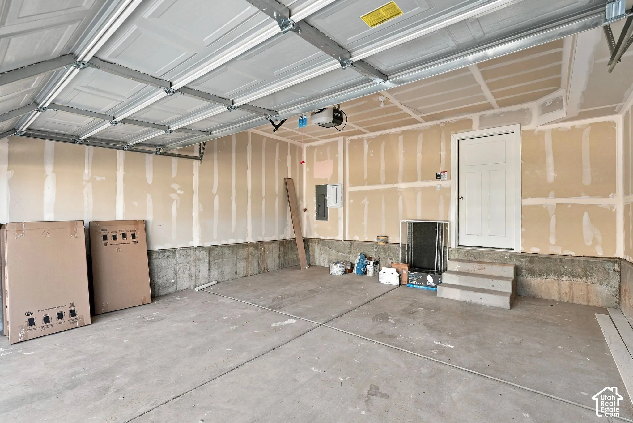 Attached garage featuring concrete flooring, an automated overhead door system, and a designated service entrance with masonry steps