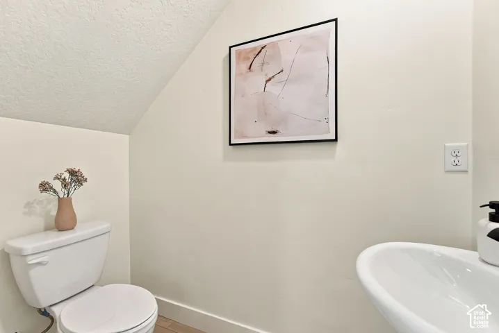 Neutral-toned bathroom featuring a porcelain toilet and a white pedestal sink
