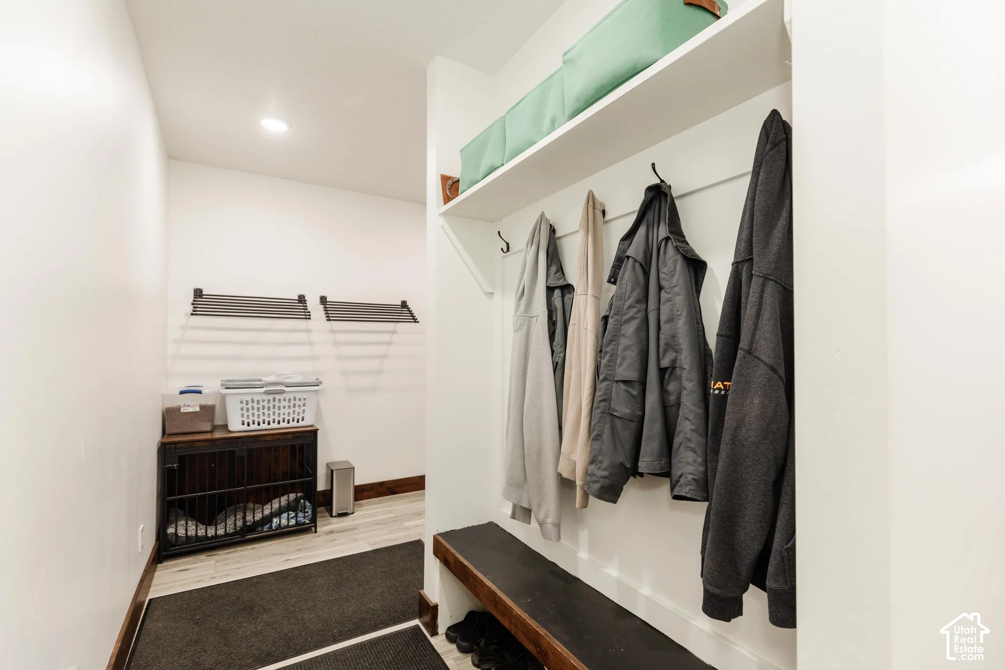 Built-in wooden bench seating, wall-mounted coat hooks, and an integrated overhead storage shelf