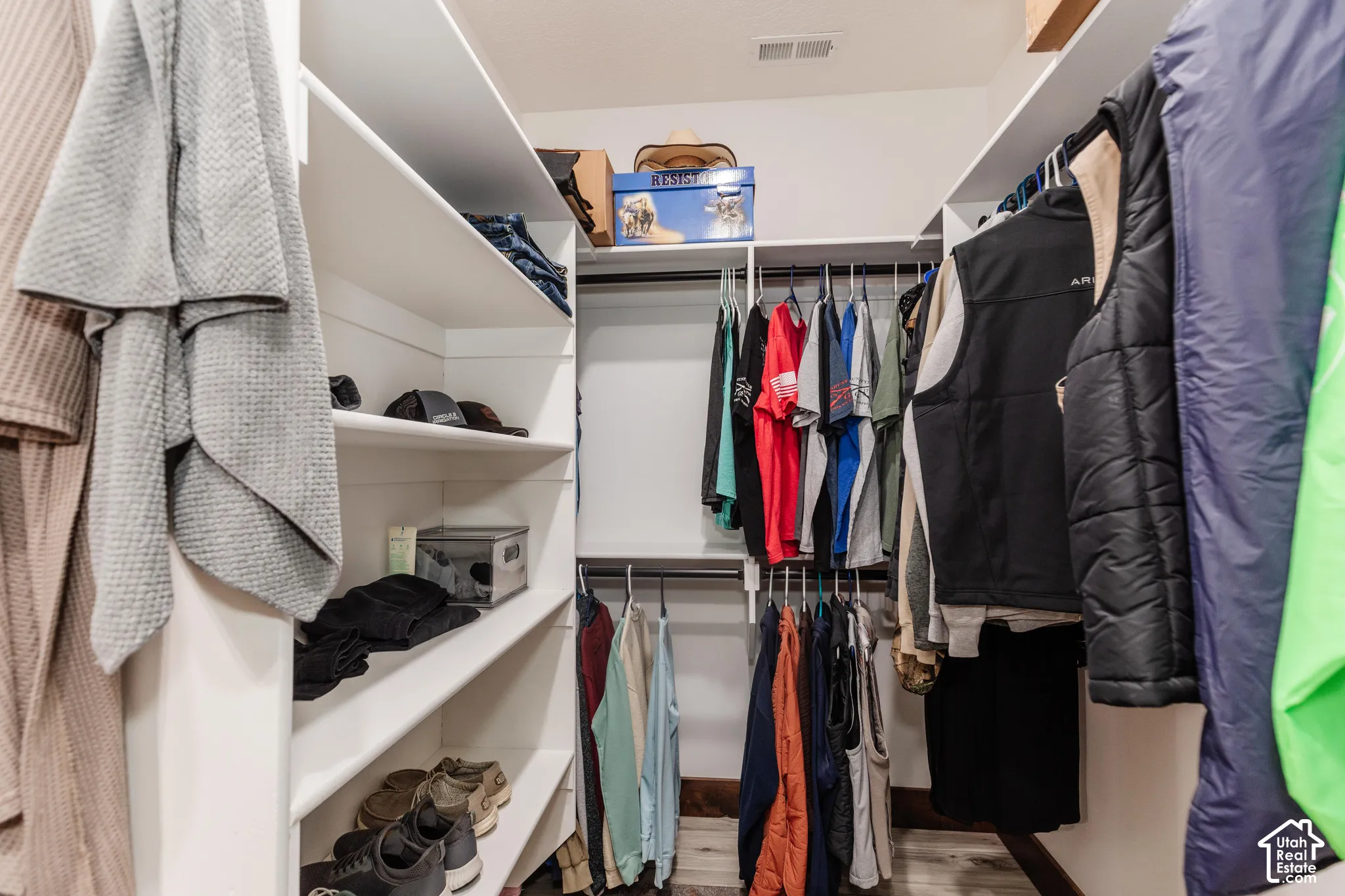 Walk-in closet featuring white built-in shelving and multi-level hanging rods