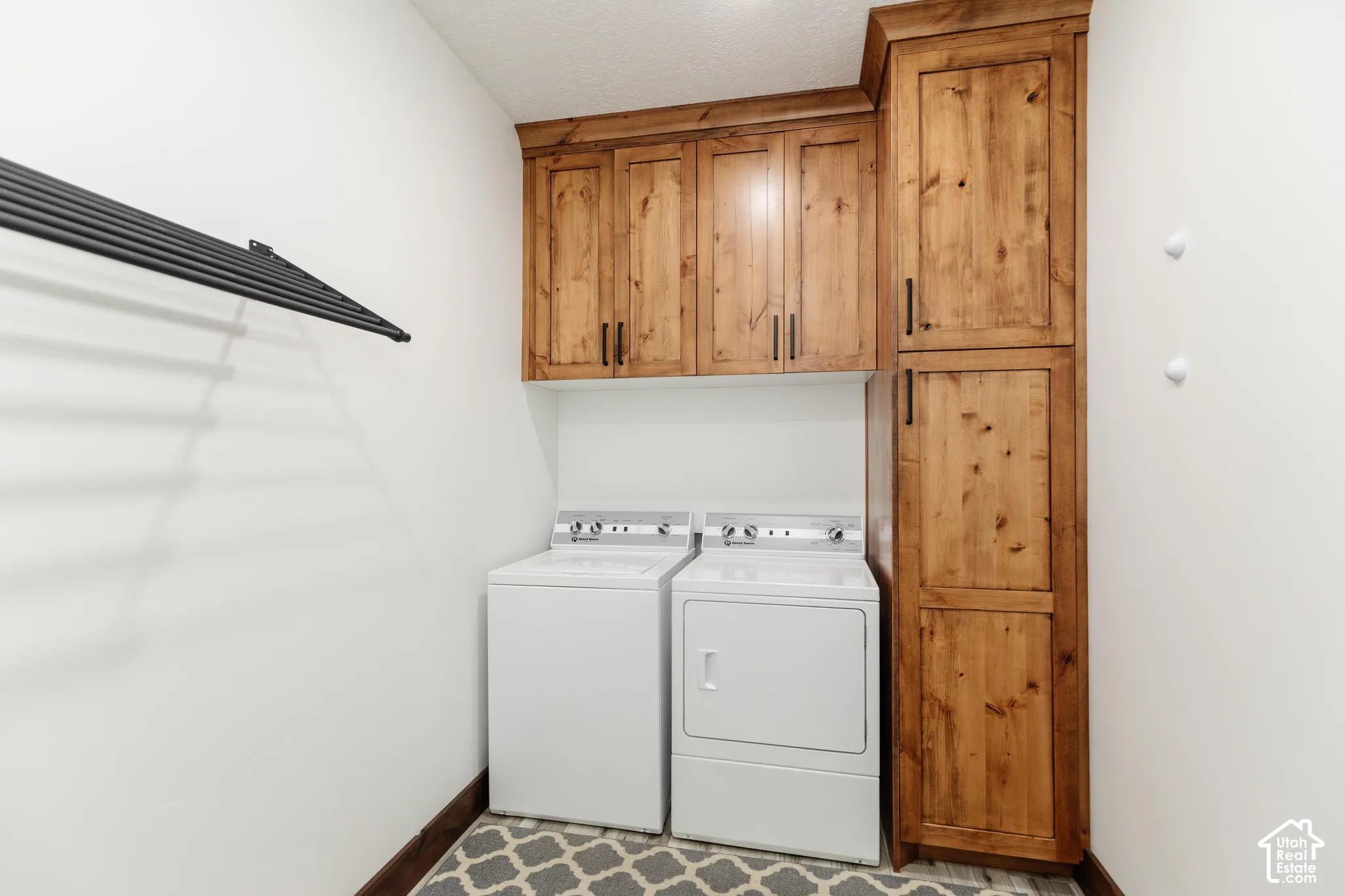 Custom wood cabinetry, floor-to-ceiling storage pantry, and mounted black metal drying rack